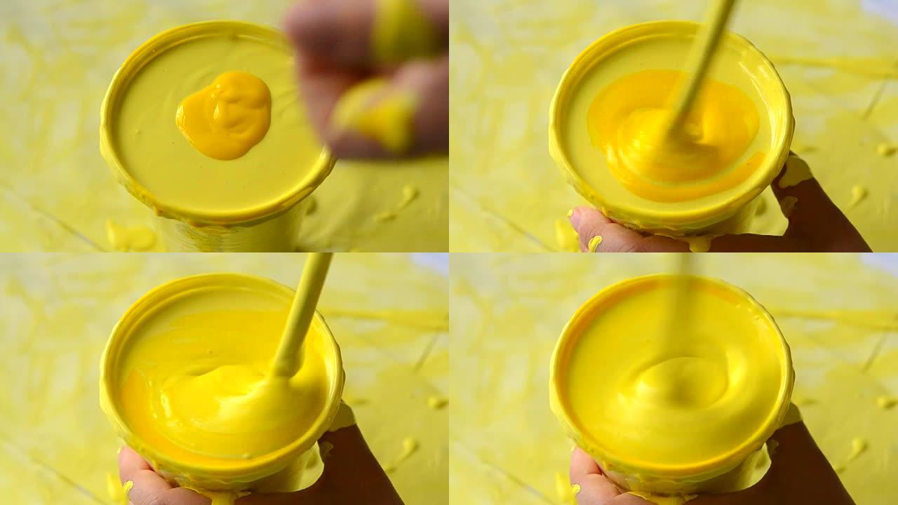 在带有黄色油漆的塑料烧杯中倒入黄色颜料并混合