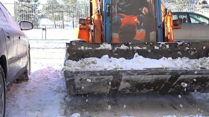 小型拖拉机在冬季清洁街区平房停车场的冬季积雪。