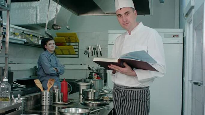 男厨师拿着食谱书，而厨师实习生赞许地点头