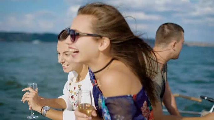 一小群朋友在游艇上聚会，大声笑着，喝着香槟在海上航行