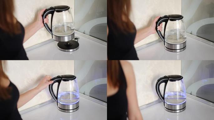 美丽的女人打开现代玻璃电水壶在豪华的当代厨房。