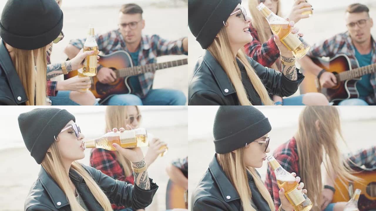 两个迷人的女孩和一个男人在岸上碰碰瓶子和喝啤酒特写镜头
