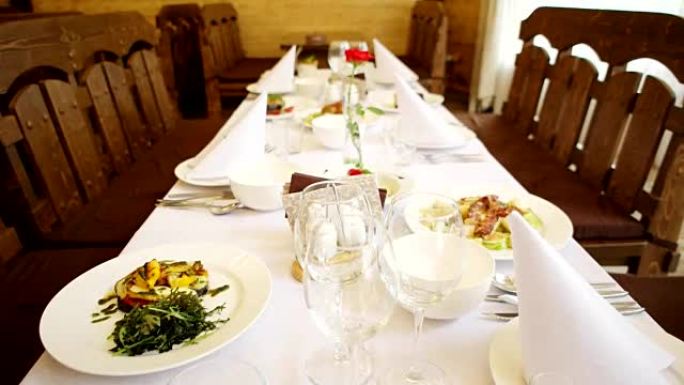 庆祝桌，桌上用餐的菜肴，叉子眼镜，刀，餐具躺在盘子附近，肉，鱼，沙拉美丽的白色桌子