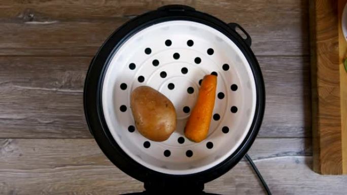 土豆和胡萝卜放在multicooker的盘子上