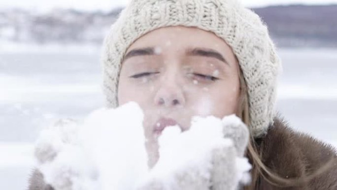 美丽快乐的女孩在户外吹雪。慢慢地