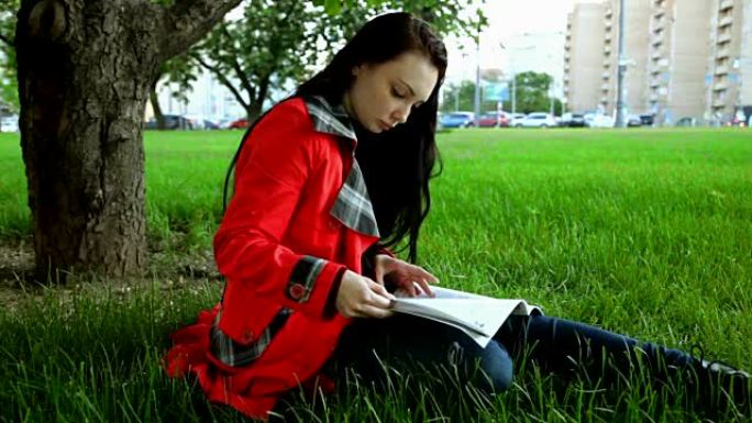 黑发女人在草地上阅读杂志