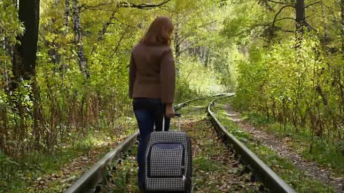 带着手提箱沿着铁路行走的女孩