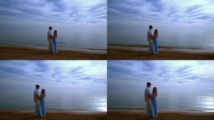 怀孕夫妇海滩。怀孕的夫妇在海边拥抱。爱情情侣海滩