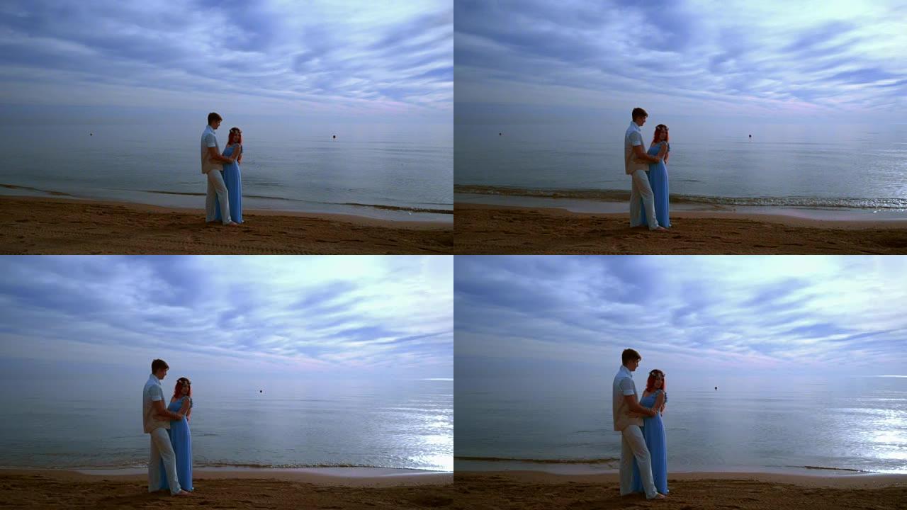 怀孕夫妇海滩。怀孕的夫妇在海边拥抱。爱情情侣海滩
