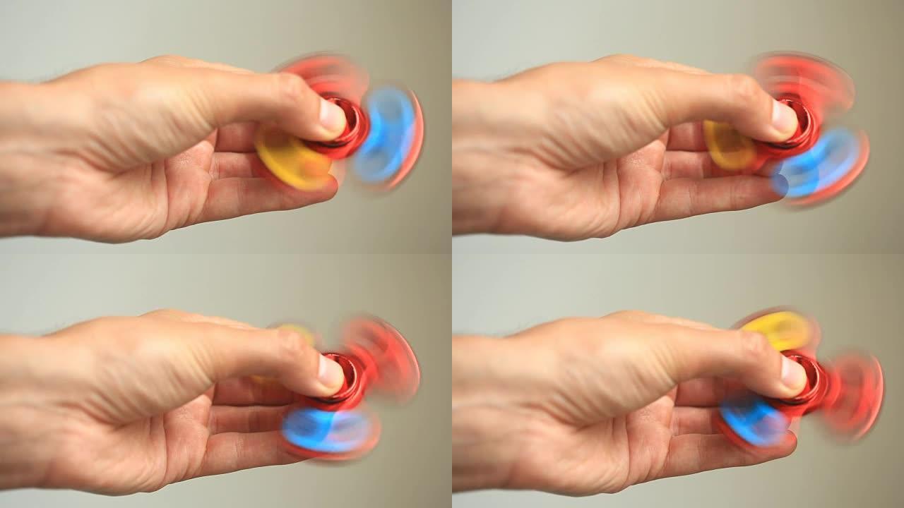 彩色，红-黄-蓝色手旋转器，或坐立不安的旋转器，在人的手上旋转。