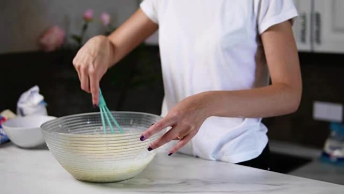 面目全非的女人用打蛋器在碗里准备面团混合配料。自制食物。慢动作镜头