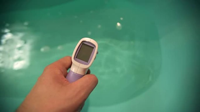用非接触式温度计测量婴儿浴室的水温