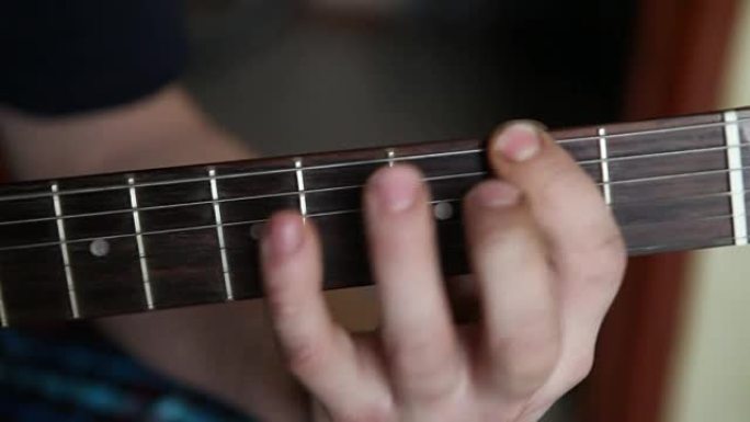 男人弹吉他，手指放在指板上