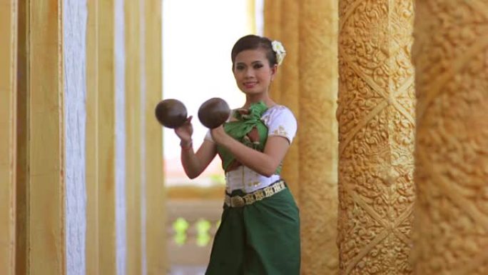 美丽的亚洲女孩在寺庙里表演椰子民间舞蹈
