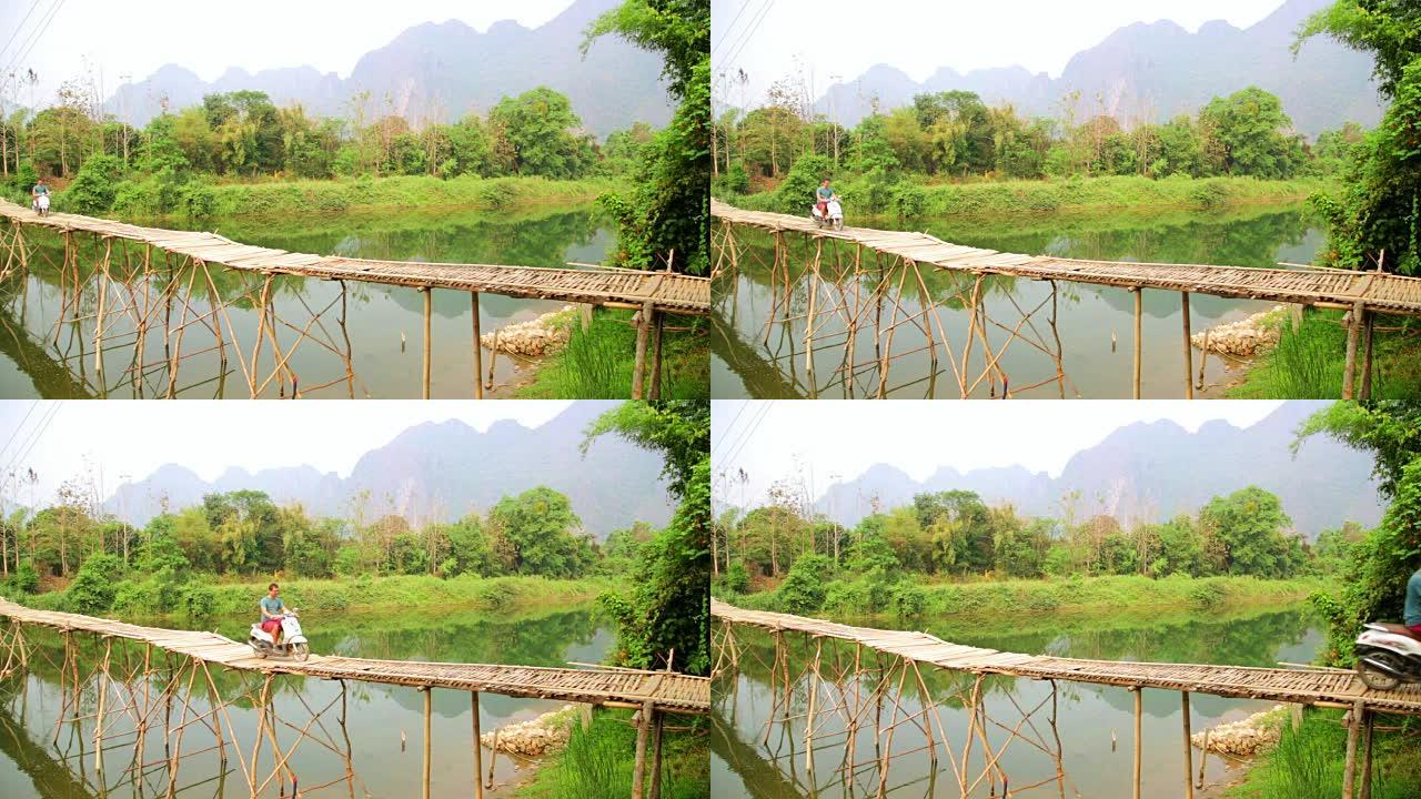 老挝石灰石景观摩托车穿越竹桥的快乐游客