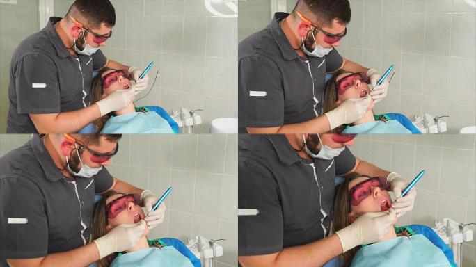 戴眼镜的正畸医生用激光使一名年轻女子的牙齿变白