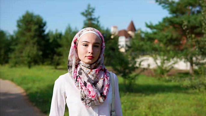 在现代化的城市里，年轻的阿拉伯妇女戴着头巾在公园里散步