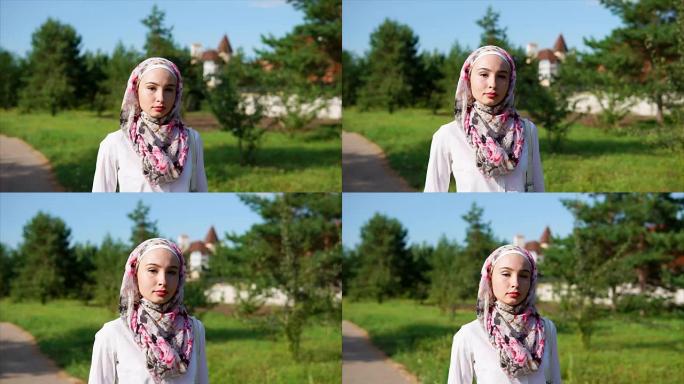 在现代化的城市里，年轻的阿拉伯妇女戴着头巾在公园里散步