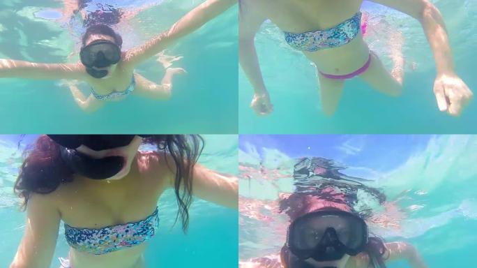 带浮潜面具的女人向摄像机游去的水下视图