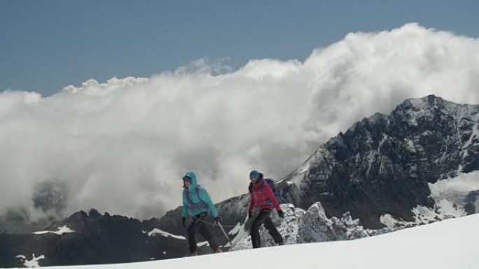 两名女性登山者越过高山的冰川山脊，并酝酿着暴风云。