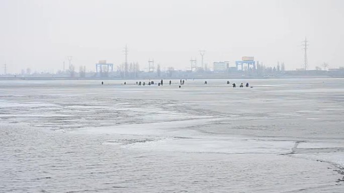 水电站背景下冻水蓄水盆冰面上的冬季垂钓者