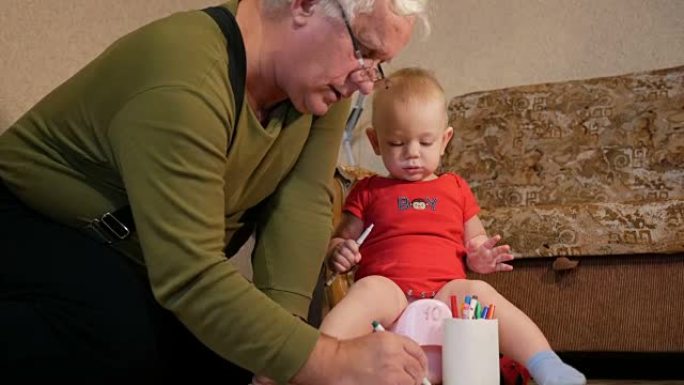 迷人的婴儿坐在锅上，用祖父的记号笔在纸上画画。男孩在家里撒尿和玩耍。孩子1年
