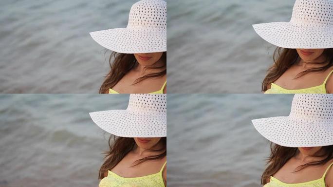 戴着眼镜和帽子的年轻女子在海边的海滩上