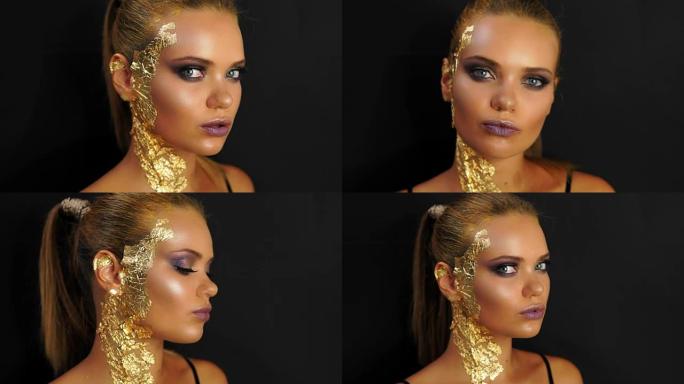 一个年轻女人的特写站在黑色的背景和看在相机。富有表现力和时尚的金色妆容和发型。皮肤上覆盖着金色的金属