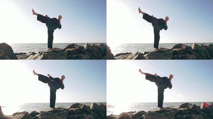 男性空手道战士在石头上摆姿势海洋背景，慢动作