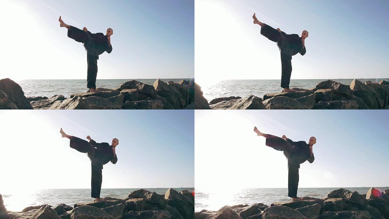 男性空手道战士在石头上摆姿势海洋背景，慢动作