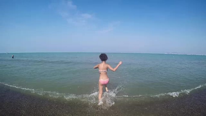 女孩跑进海里飞溅慢动作的手持镜头