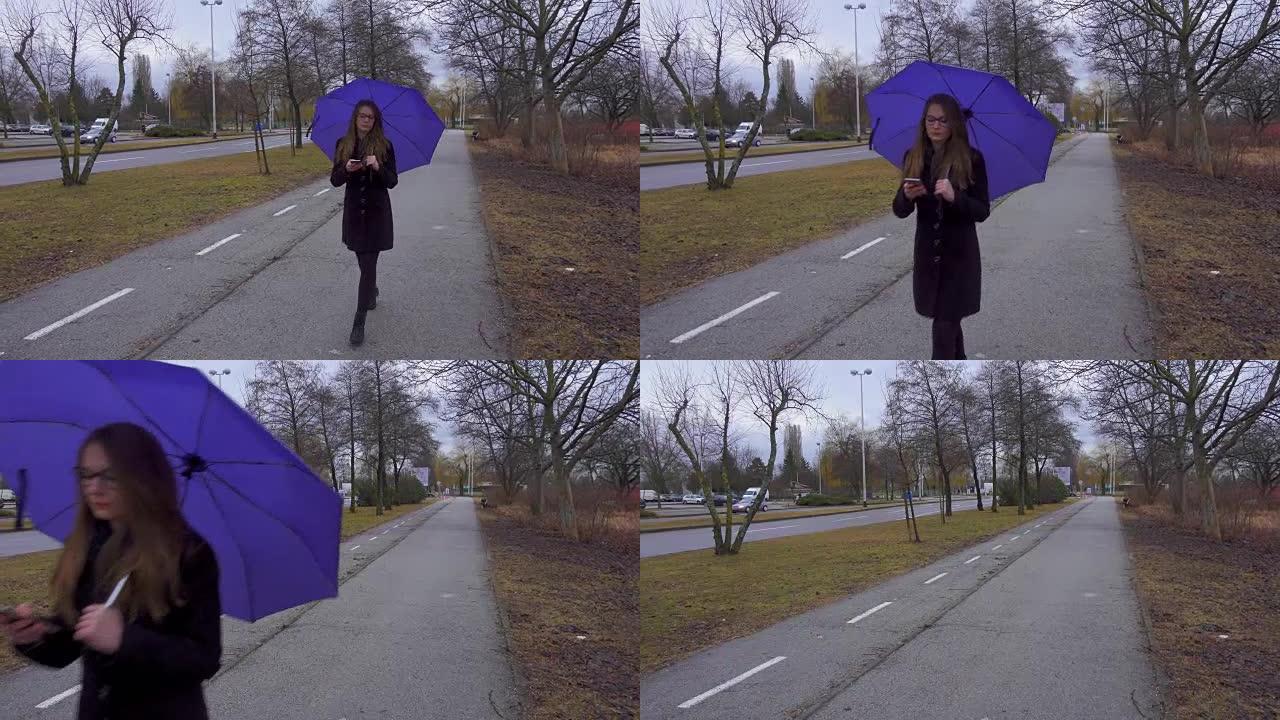 使用智能手机带伞的年轻女子