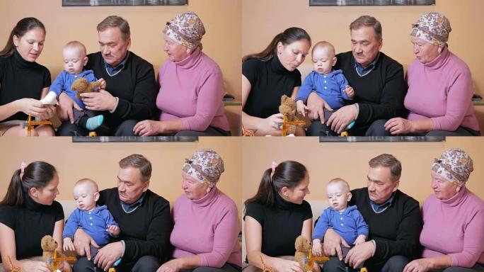 有一个婴儿的幸福大家庭她的母亲和祖父母在沙发上玩得开心。他们彼此欢笑和交谈。家庭幸福的概念