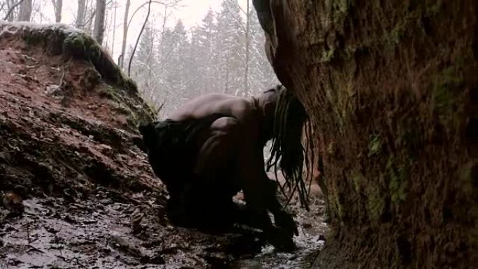 史前穴居人在冬季森林的背景下在他的洞穴中洗涤