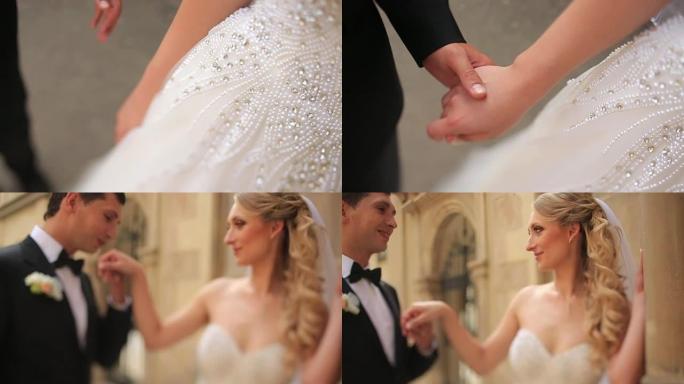 年轻的新娘和新郎在他们的婚礼上快乐。新郎轻吻美丽的金发新娘的手。背景是Sunny Lviv
