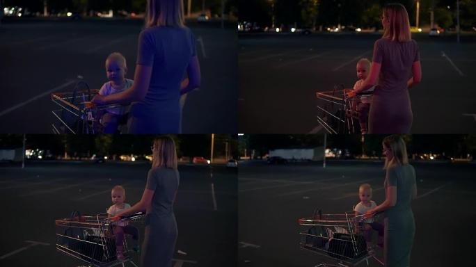 小婴儿坐在杂货店的手推车上，而她的母亲在购物后寻找汽车后，将手推车向前推，在超市旁边的停车场走