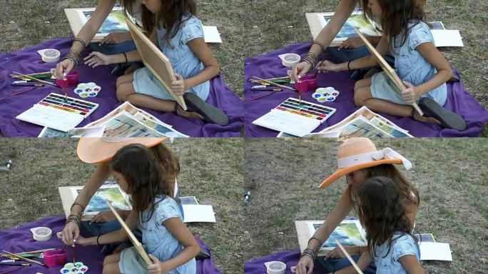 有女儿的女人在公园用水彩画绘画