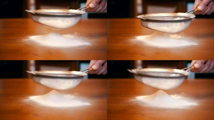 在家庭厨房的木桌上通过筛子筛分面粉。慢动作