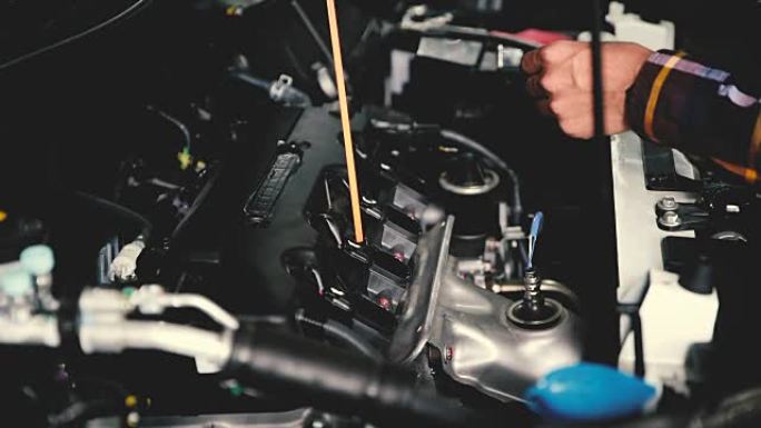 手的慢动作从深棒检查汽车发动机的润滑油油位，以达到维修和保养的概念。