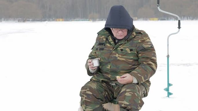 冬天，一个人在湖上钓鱼，用热水瓶喝茶。他用热饮吃饼干