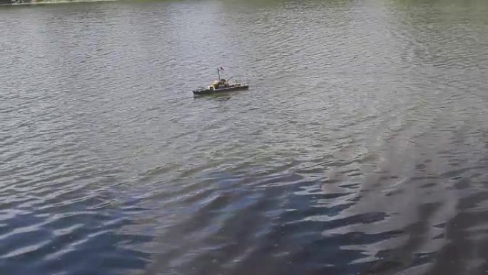 人们在池塘里驾驶遥控木制游艇。