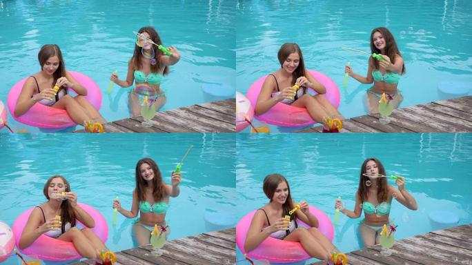 可爱的女孩坐在游泳池的充气戒指上做泡泡，夏季派对，穿着泳衣的朋友休息