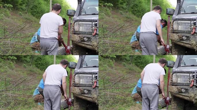 两名旅客在森林肮脏的道路上更换了expeditionaty SUV的车轮。