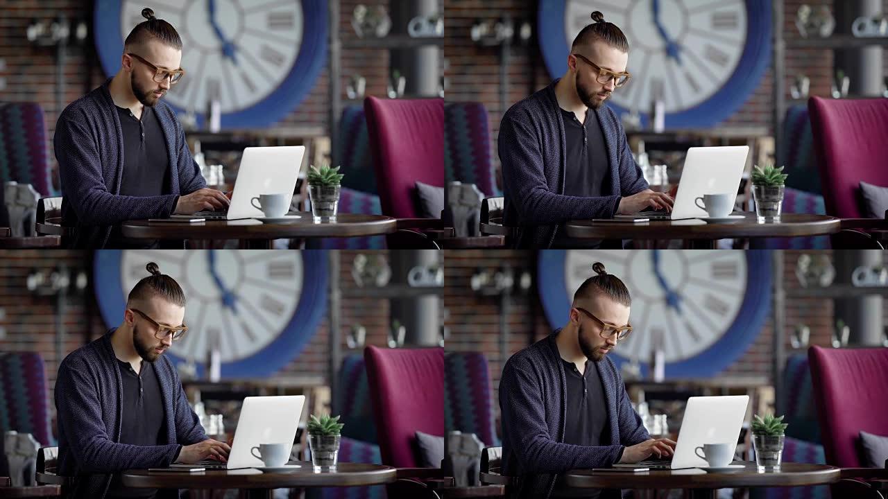 一位认真的作家在笔记本电脑的键盘上打印了想到的纪录片小说的文字，一个戴着眼镜的视力不好的男人正坐在餐