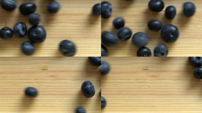 许多蓝莓在木质表面滚动。慢动作。顶视图。