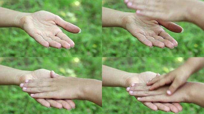 母女双手放在绿色背景上。三只手在一起