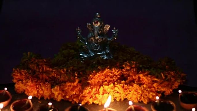 甘尼萨勋爵 (lord ganesha) 与粘土油灯和鲜花，ganesh chaturhti节并为印
