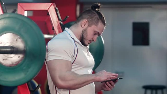 肌肉发达的人在锻炼之间在健身房使用电话