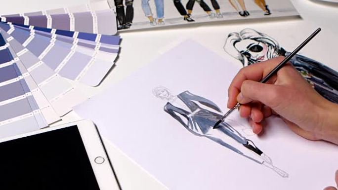 时装设计师在裙子的草图上画笔。特写