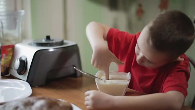 一个小男孩用手指吃奶油。